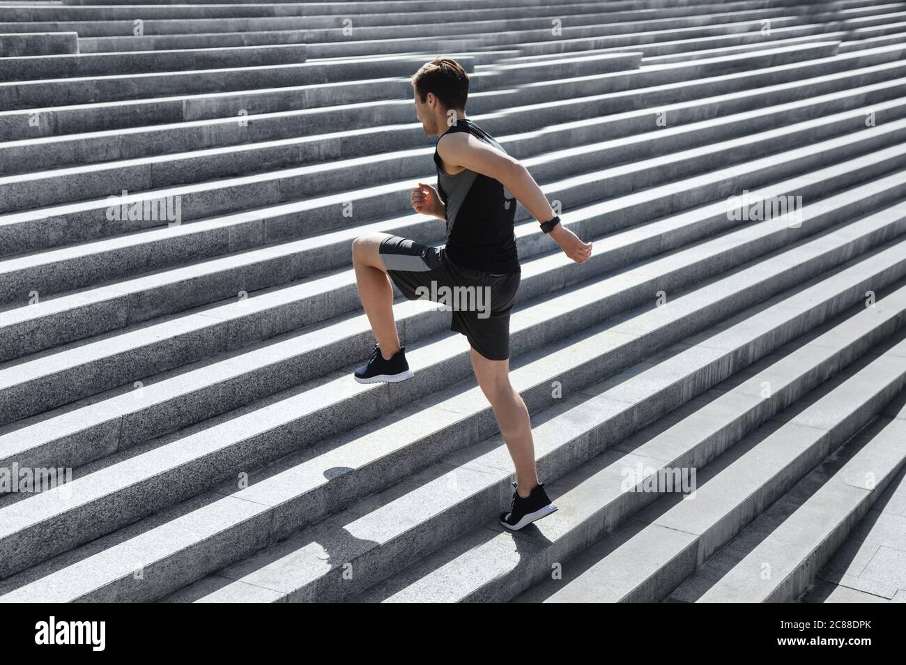 Cardio-Training. Kerl macht Übungen und läuft die Treppe hoch, seine Beine hoch Stockfoto