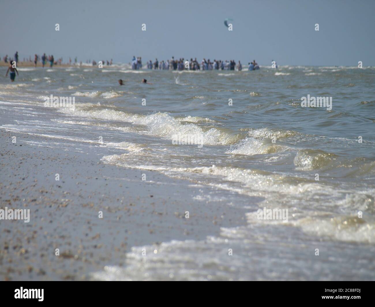 Ruhige Wellen am Strand der Nordsee in Katwijk/NL. Entfernte Menschen im unscharfen Hintergrund Stockfoto