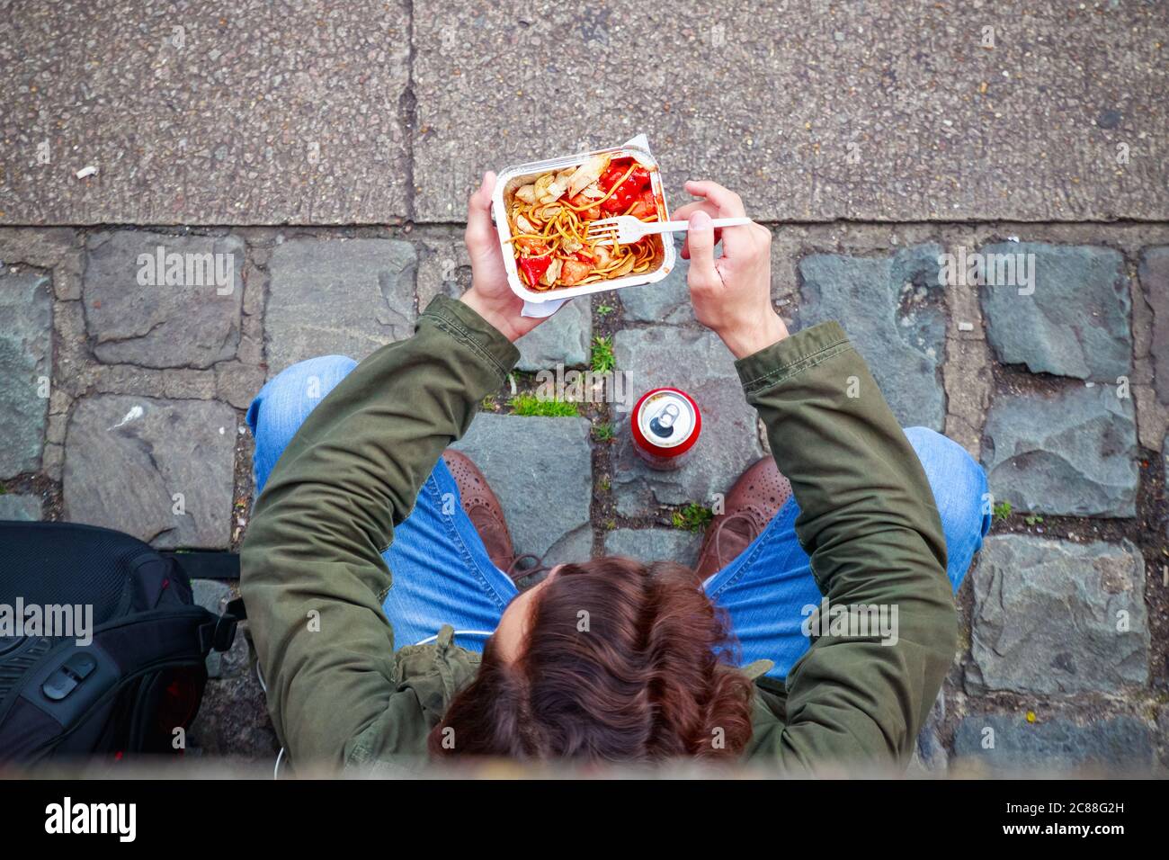 Blick von oben auf einen männlichen Touristen, der auf der Straße am Camden Market in London chinesisches Essen zum Mitnehmen isst Stockfoto