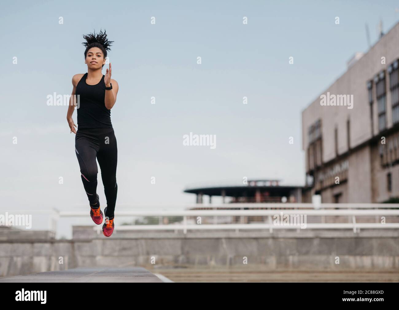 Laufen, springen und fliegen. Sportliche schlanke afroamerikanische Mädchen in modischen Sport Uniform gefroren in der Luft Stockfoto