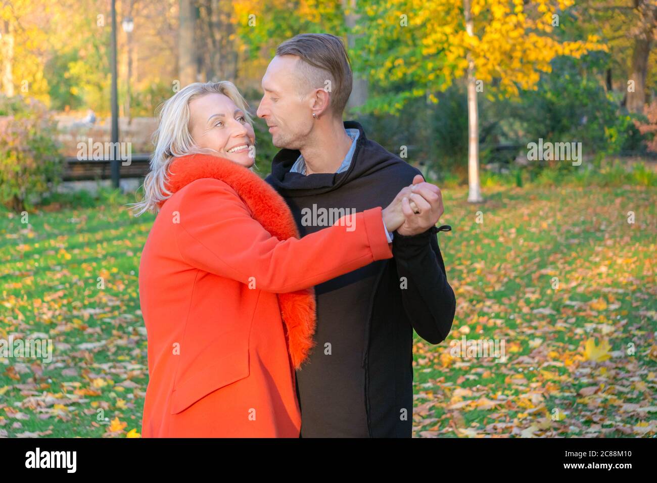 Paar mittleren Alters, die Spaß im Herbstpark haben. Tanzendes Paar auf Herbst Bäume Hintergrund. Mann und Frau umarmen sich auf bunten Park. Glückliche Familie in der Natur Stockfoto