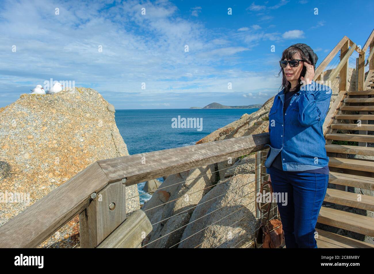 Eine einzige weibliche Touristen eine hölzerne Treppe, die die spektakuläre Felsformation auf Granite Island in Victor Harbor in Südaustralien bewundert. Stockfoto