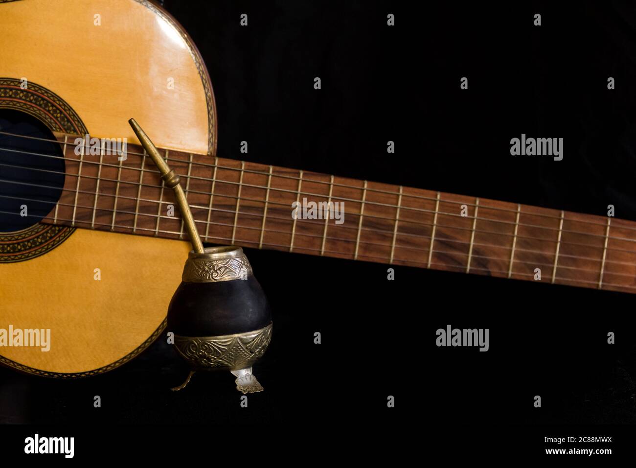 Mate und Gitarre, Konzept der argentinischen Folklore, isoliert auf schwarzem Hintergrund Stockfoto