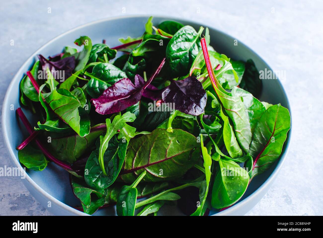 Gemischte frische Salatblätter in einer blauen Schüssel Draufsicht Stockfoto