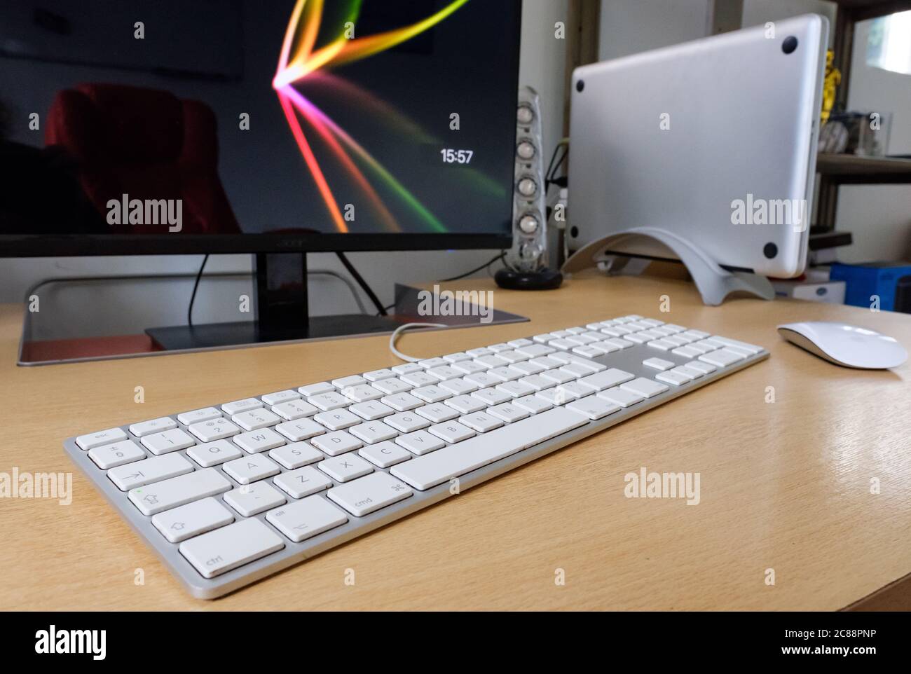 Detailansicht eines Laptops mit einer großen Tastatur, einer drahtlosen Maus und einem Computermonitor, der auf einem Schreibtisch verwendet wird. Stockfoto