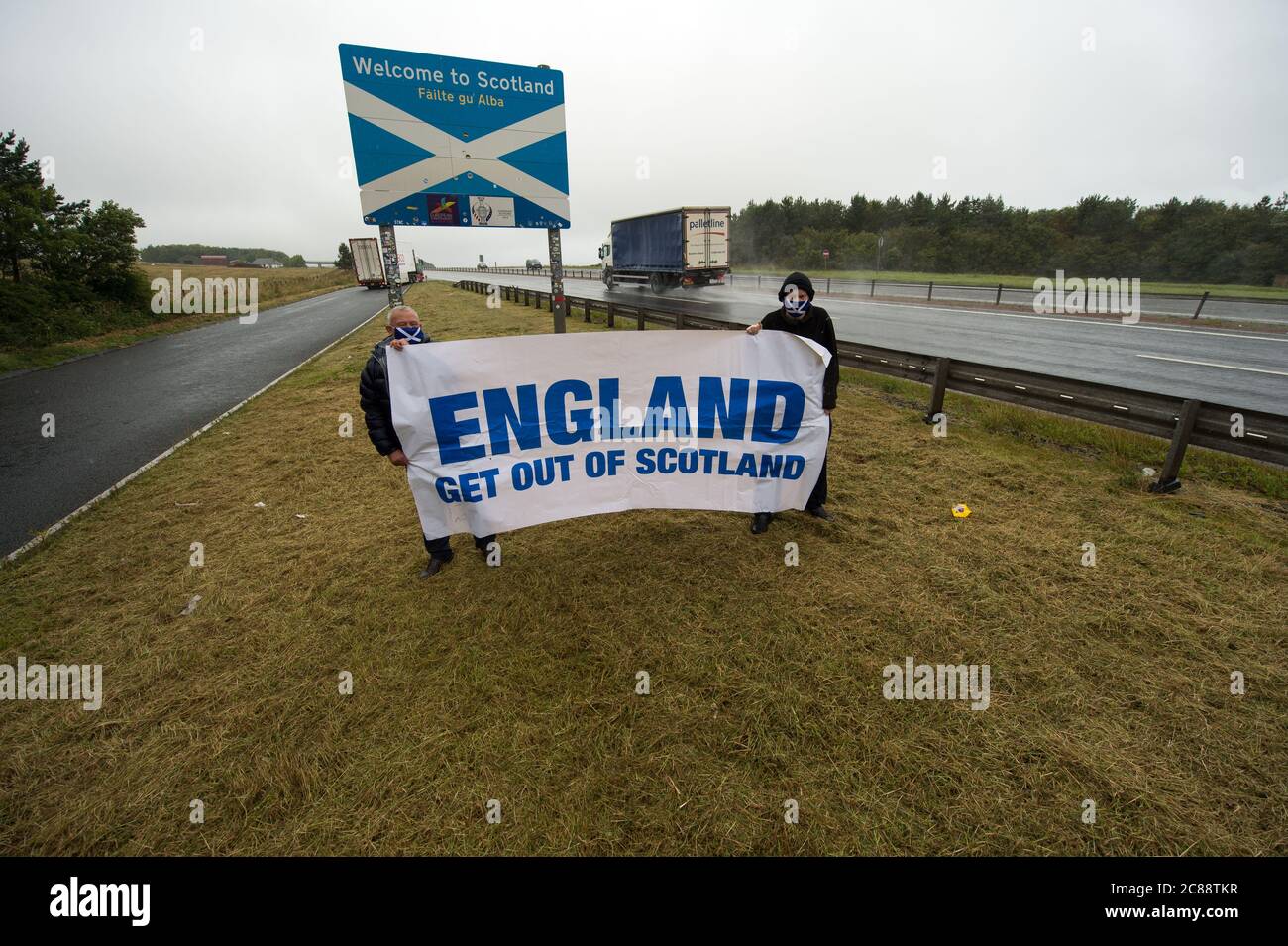 Schottisch/Englisch Grenze in Berwick, Schottland, Großbritannien. 22. Juli 2020 Foto: (L-R) James Connelly; Sean Clerkin von Action for Scotland. Alle Menschen müssen aufhören, von England nach Schottland zu reisen, aus unwesentlichen Gründen, um die schottische Bevölkerung vor Covid-19 zu schützen. Neue Fälle von Covid-19 sind 5.5-mal höher in England als Schottland und Professor Rowland Kao ein mathematischer Biologe an DER UNIVERSITÄT EDINBURGH erklärte kürzlich, dass, wenn es erhöhte Reisen zwischen England und Schottland ist es unvermeidlich, dass Fälle von Covid-19 wird in Schottland zunehmen. Quelle: Colin Fisher/Alamy Live News. Stockfoto