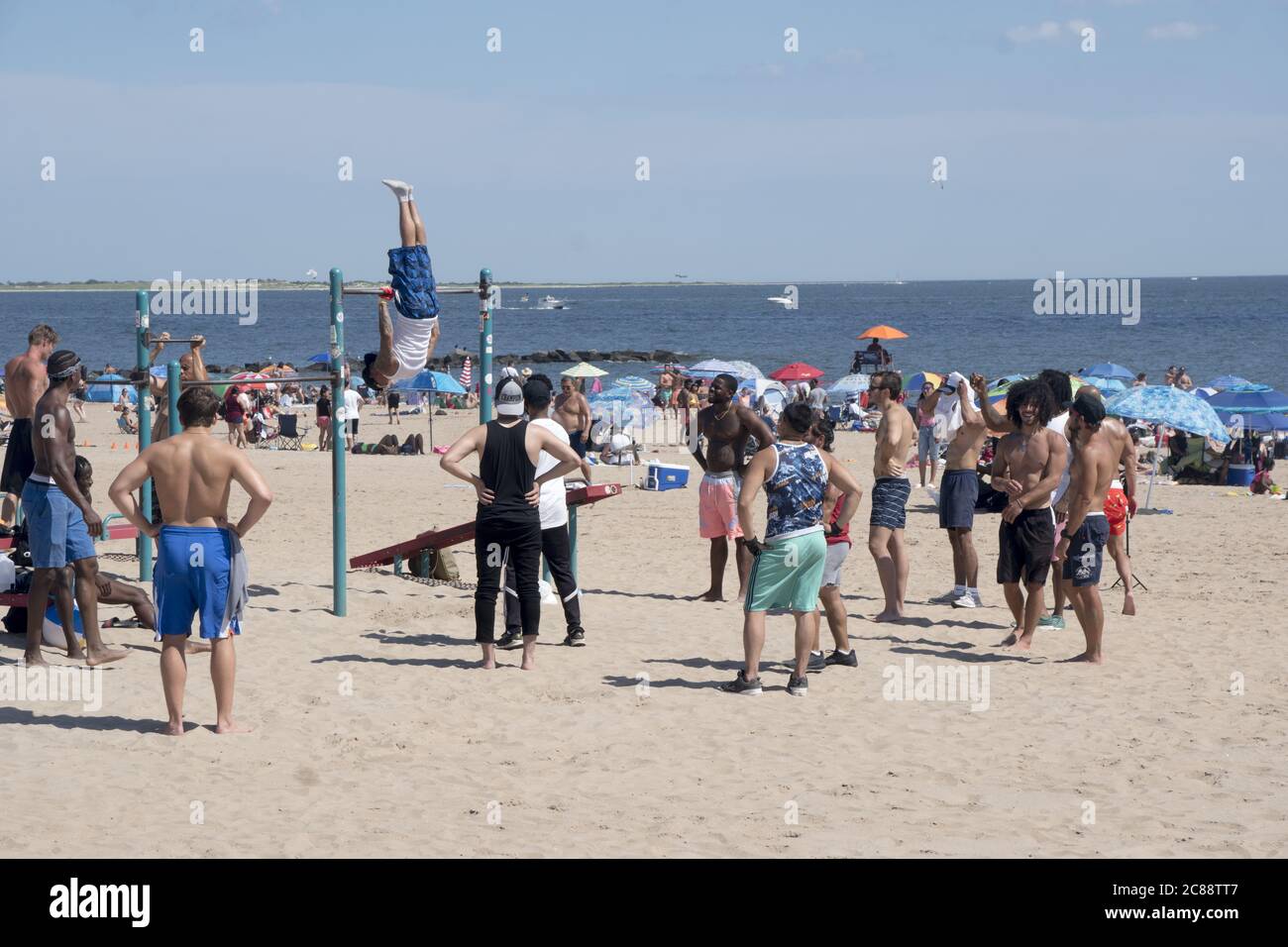 Junge Musclemen trainieren und beobachten andere am Strand von Coney Island während der Covid-19 Pandemie. Die meisten tragen keine Masken oder sorgen sich um soziale Distanzierung. Stockfoto