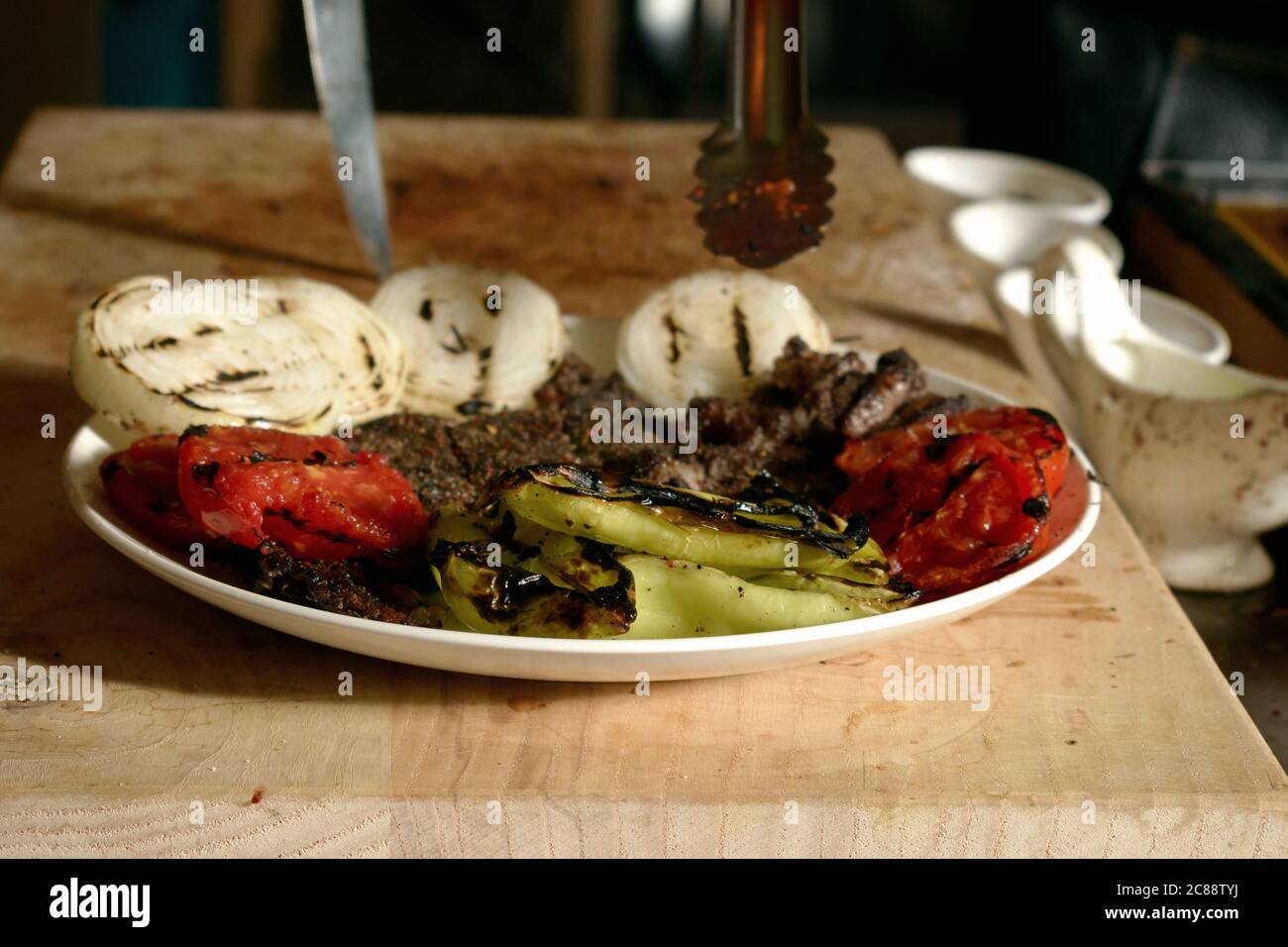 Gebratenes Fleisch mit gegrilltem Gemüse auf einem Teller, auf einem Holzbrett Stockfoto