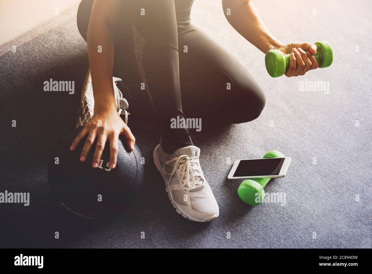 Sportliche Frau mit Smartphone beim Training zu Hause im Wohnzimmer.Online Personal Trainer oder auf Handy.Sport- und Freizeitkonzept. Stockfoto