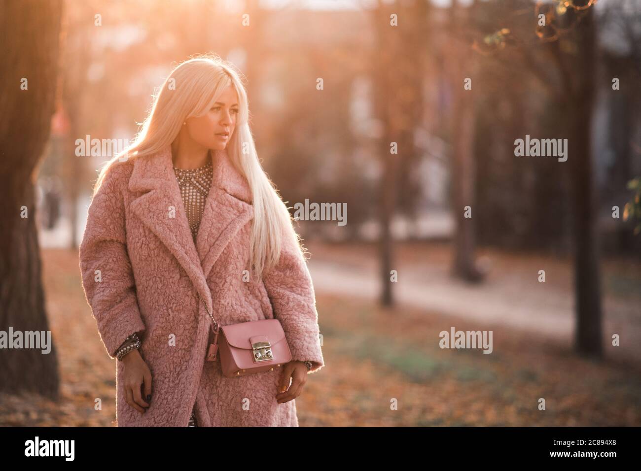 Stilvolle Frau 24-25 Jahre alt trägt trendige Wintermantel posiert im Park im Freien. Wegschauen. Wintersaison. Stockfoto