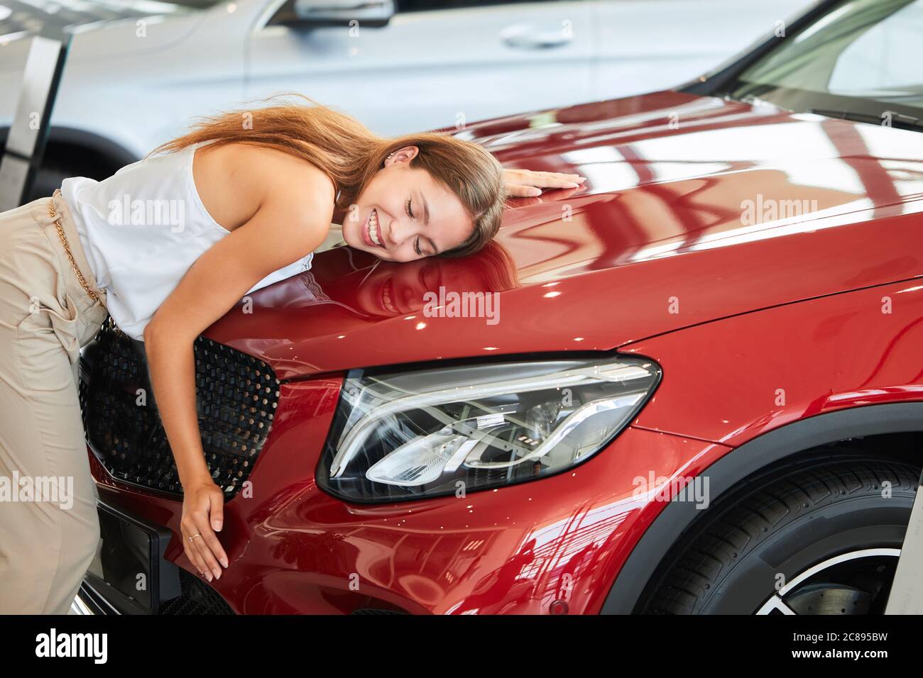Weibliche Geschäftsmann liebt ihr neues Auto, umarmt und drückt sich auf Auto  Haube im Auto Show-Raum Stockfotografie - Alamy