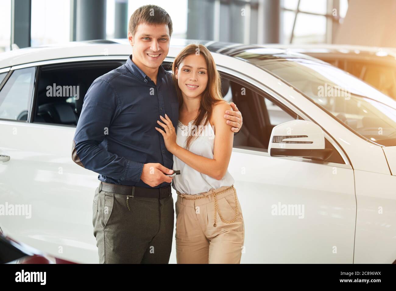 Jetzt ist Ihr Traum wird wahr. Erfolgreiche Mann kauft ein Auto für seine liebevolle modische Frau an Auto Motor Show, die ein Geschenk für ihren Jahrestag Stockfoto