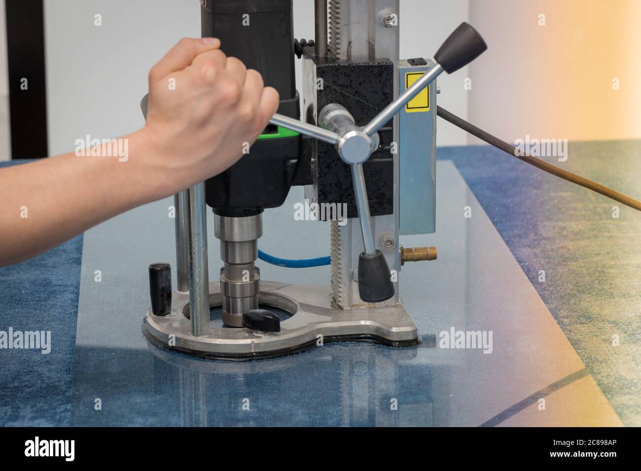 Ein Arbeiter bohrt ein Loch in das Glas. Stockfoto