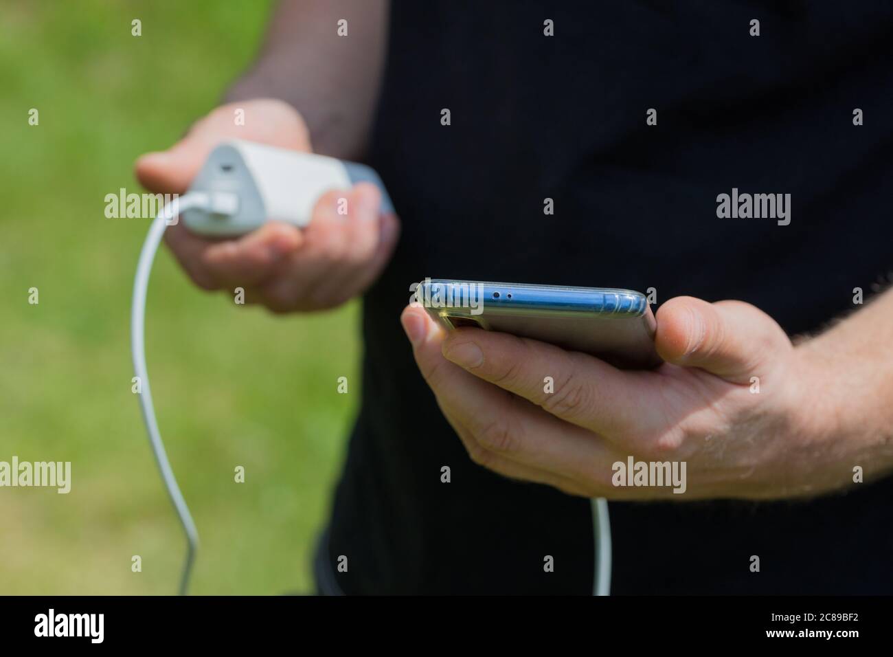 Ein junger Mann lädt das Telefon mit einer Outdoor-Powerbank Stockfoto