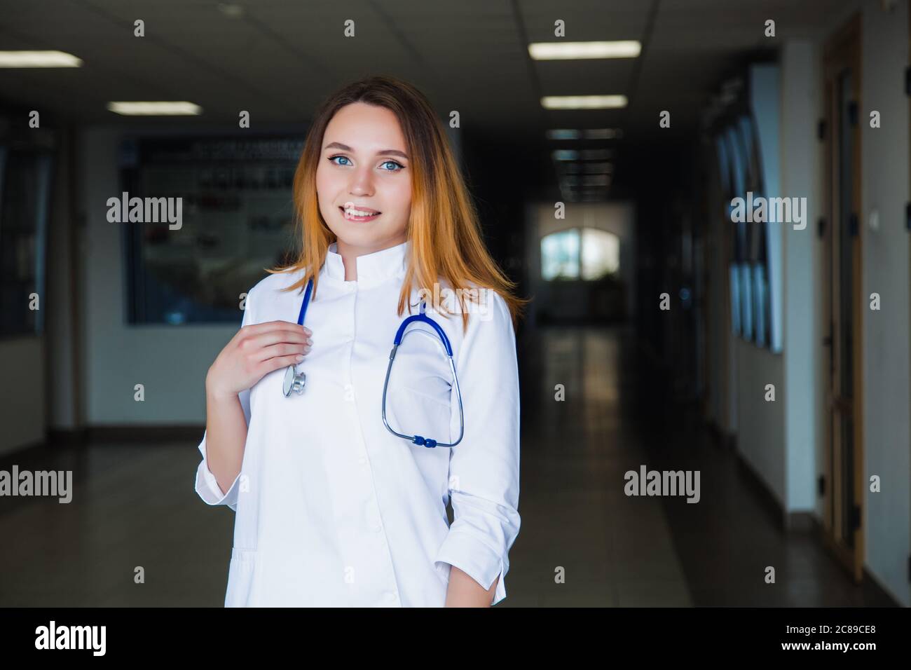 Medizinstudentin lächelt an der Kamera an der Universität in einem weißen OP-Anzug. Professionelle Mädchen Chirurg Arzt. Stockfoto