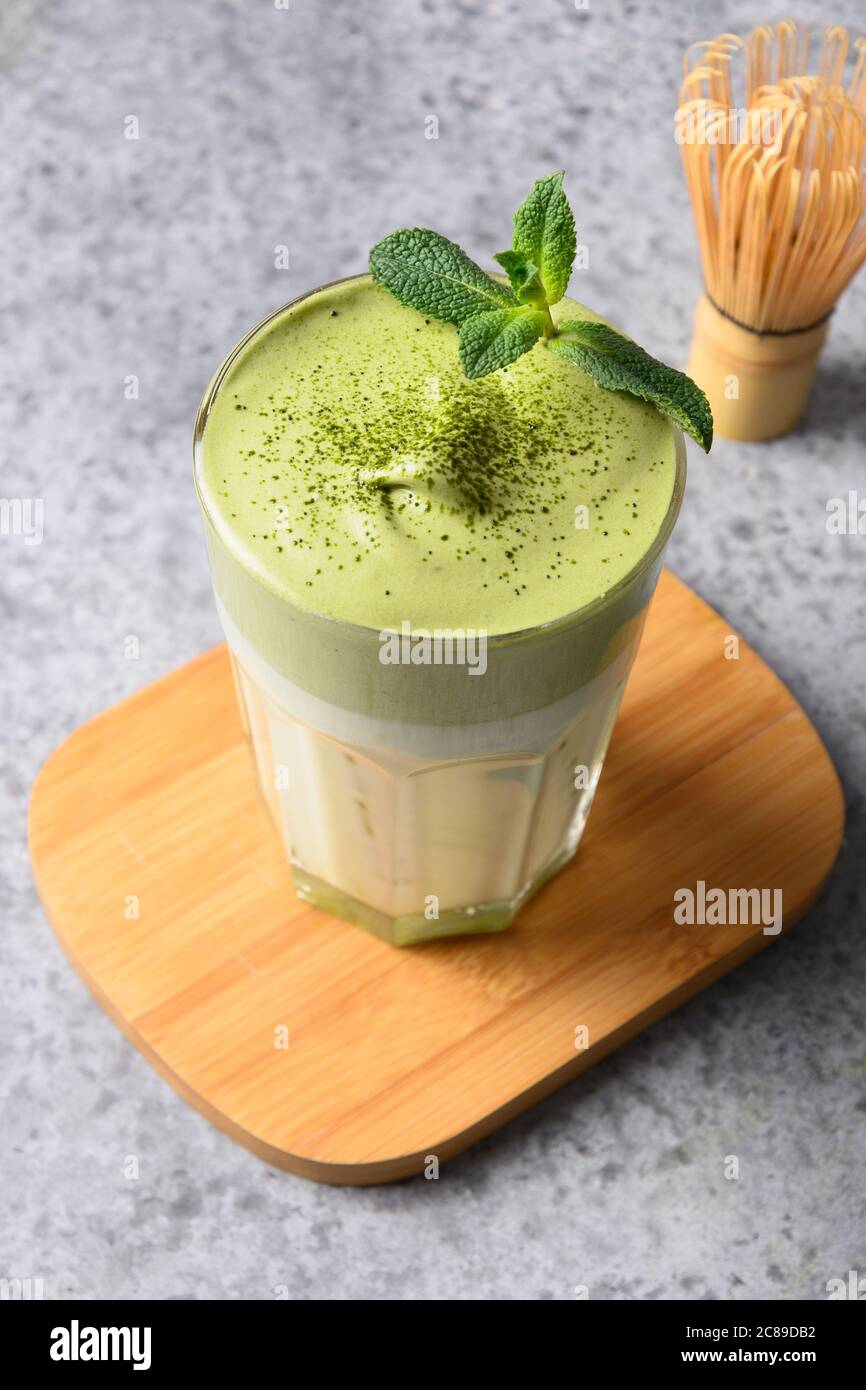 Glas Dalgona Eistee Matcha Tee und Bambus auf grau. Stockfoto
