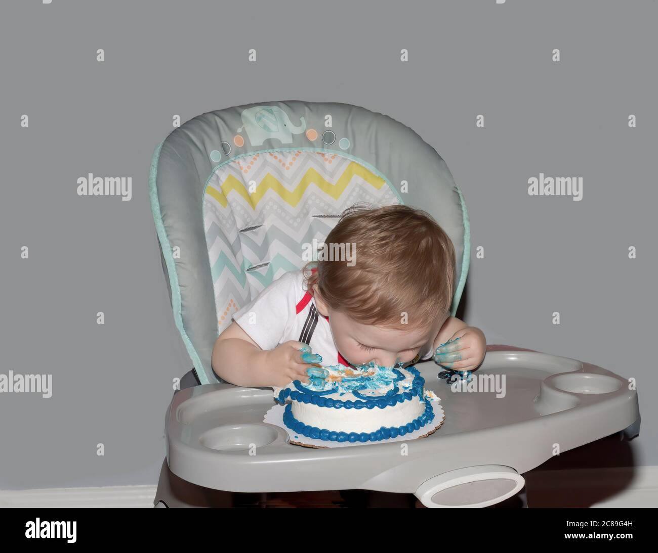 Kleinkind taucht Gesicht zuerst in eine zerschlagenen Kuchen an seinem ersten Geburtstag. Stockfoto