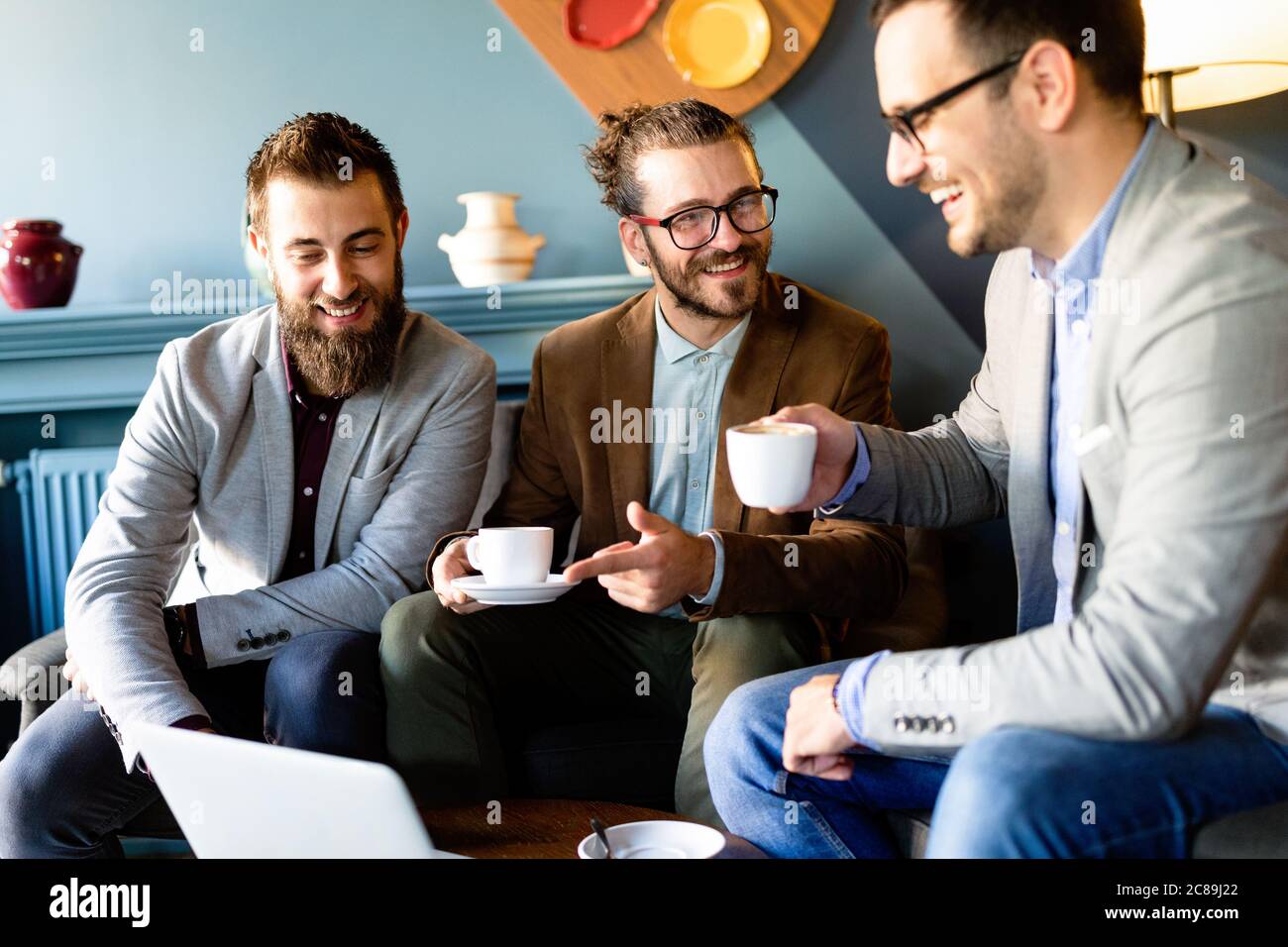 Fröhliche Geschäftsleute mit Laptop bei der Sitzung Stockfoto