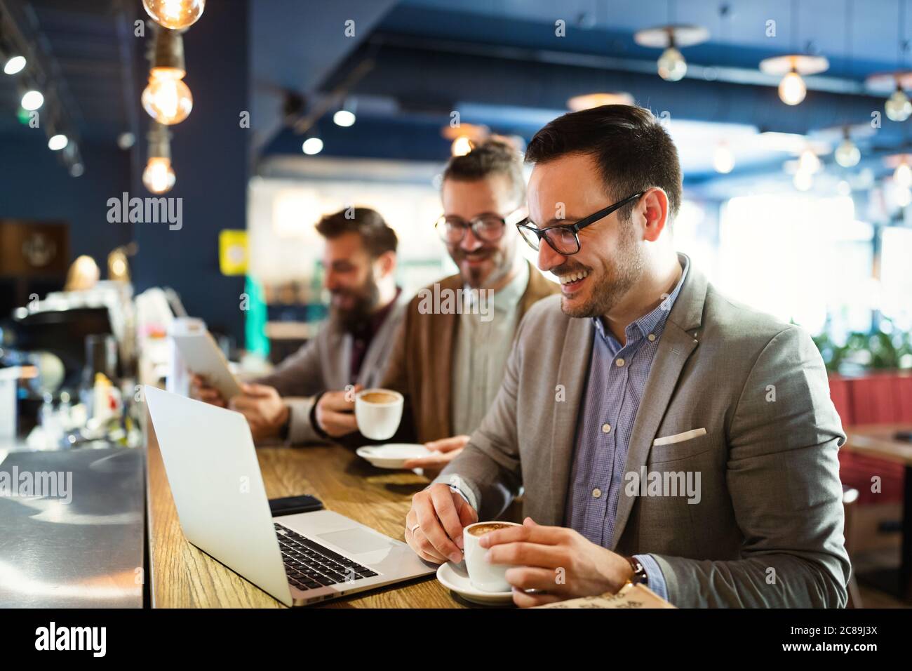 Fröhliche Geschäftsleute mit Laptop bei der Sitzung Stockfoto