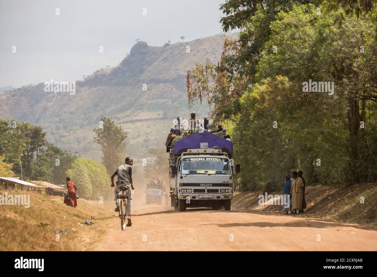 Lastwagen fahren auf steilen Mt. Elgon Bergstraßen voll mit Passagieren und landwirtschaftlichen Produkten in Bulambuli Dist., Uganda, Afrika. Stockfoto