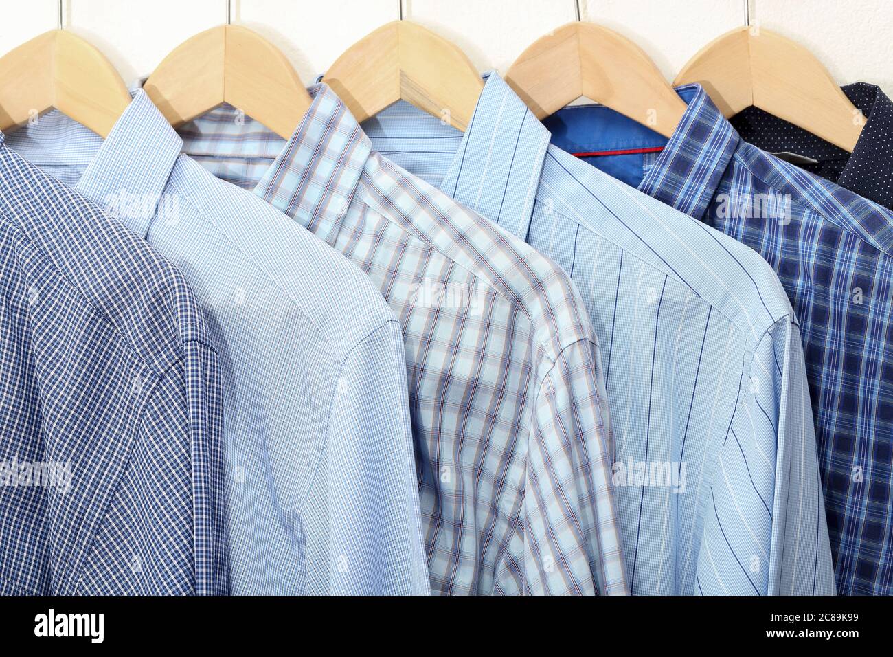Kollektion von blauen Hemden auf Kleiderbügel, Herrenmode Stockfoto
