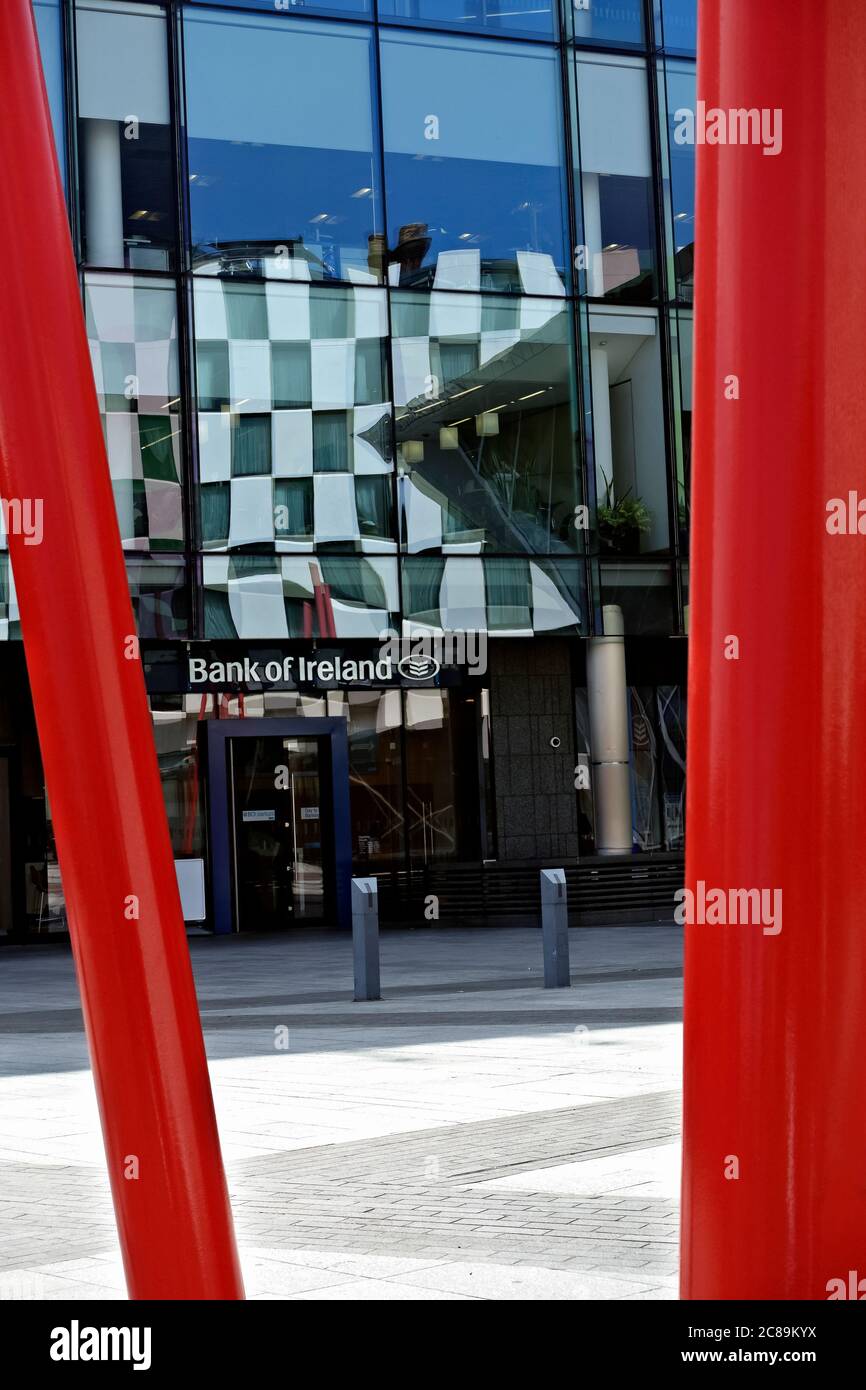 Bank of Ireland am Grand Canal Square. Spiegelung der umliegenden Gebäude in seiner Glasfront. Rote Säulen im Vordergrund. Dublin, Irland Stockfoto