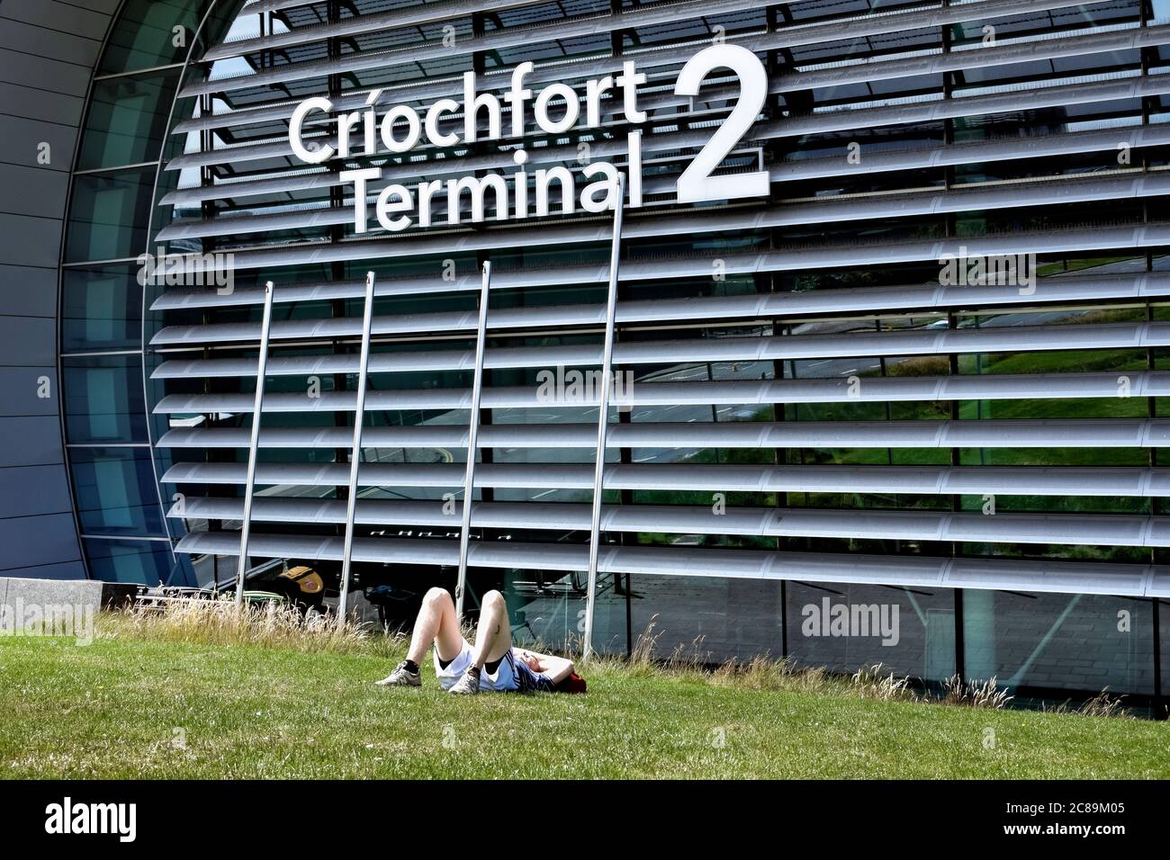 Neues Terminal 2, T2 Criochfort Dublin International Airport DUB. Junger Mann in Shorts, ruht, auf dem Gras liegend. Republik Irland, Europa, EU. Stockfoto