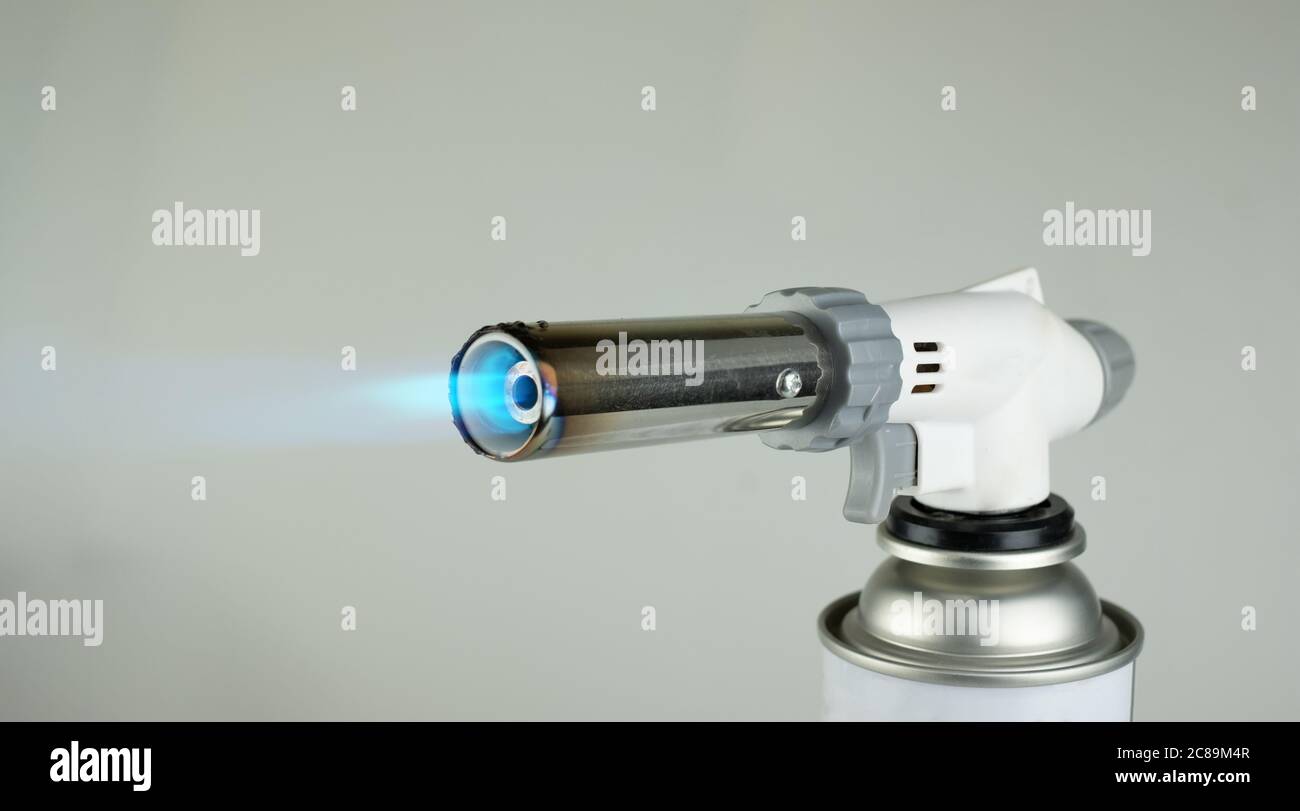 Gasbrenner mit blauer Feuerflamme auf grauem Hintergrund Stockfoto