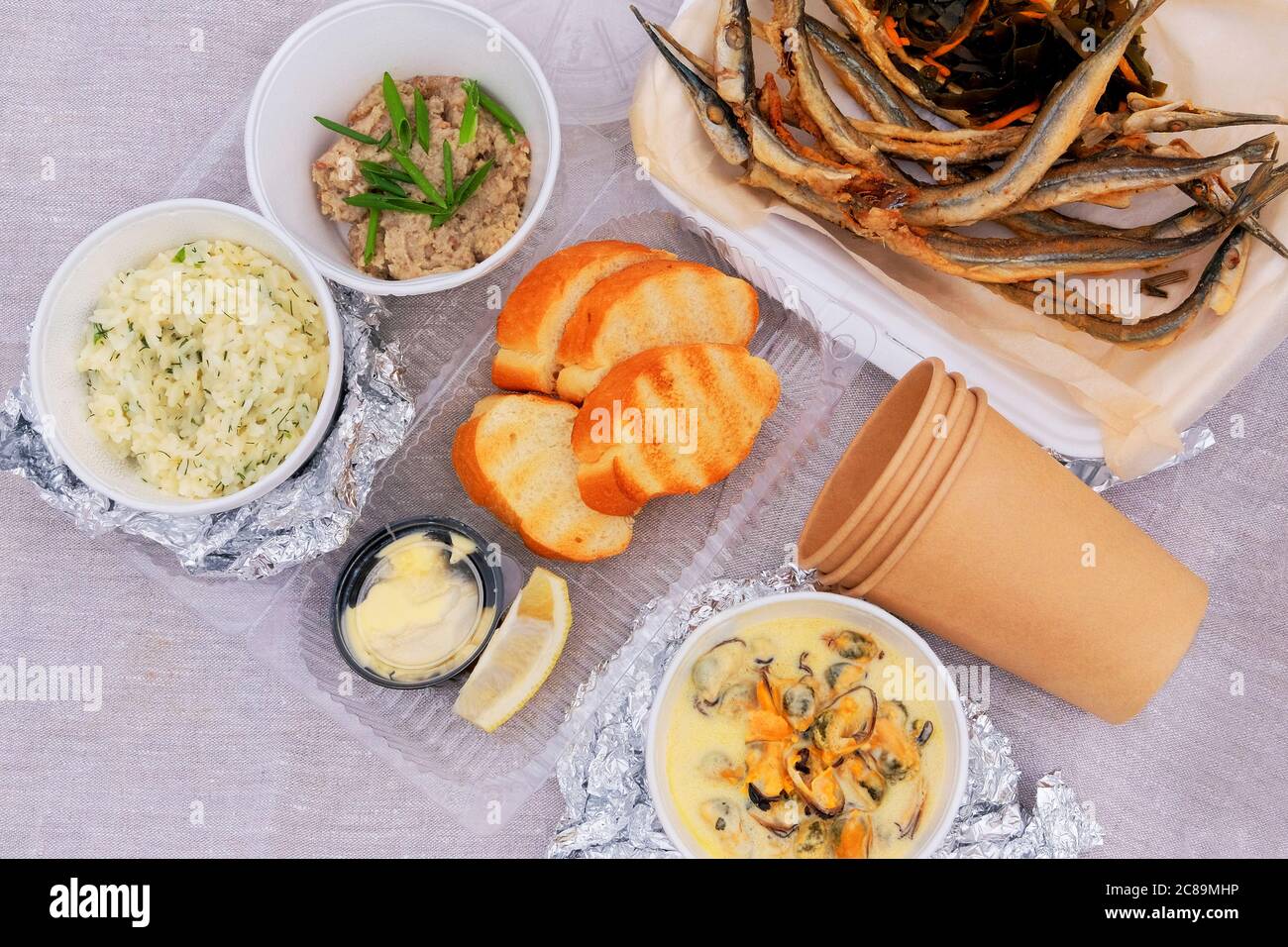 Gebratener Geruch auf einem Picknick, Nahaufnahme. Kleine Fische, Zitrone, Seeskohl, Croutons, Reis, Hackfleisch und Muscheln. Blick von oben. Stockfoto