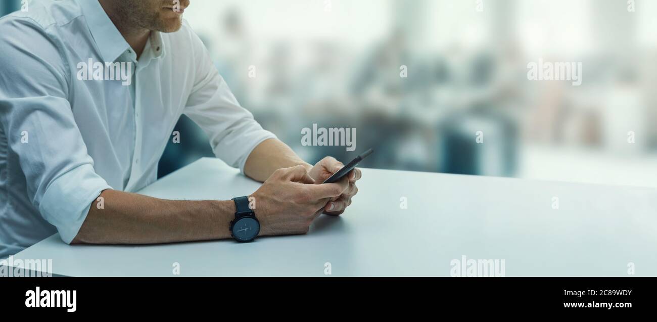 Telekommunikation - junger Geschäftsmann mit Telefon am Schreibtisch in modernen Büro. Business Hintergrund Kopie Raum Stockfoto