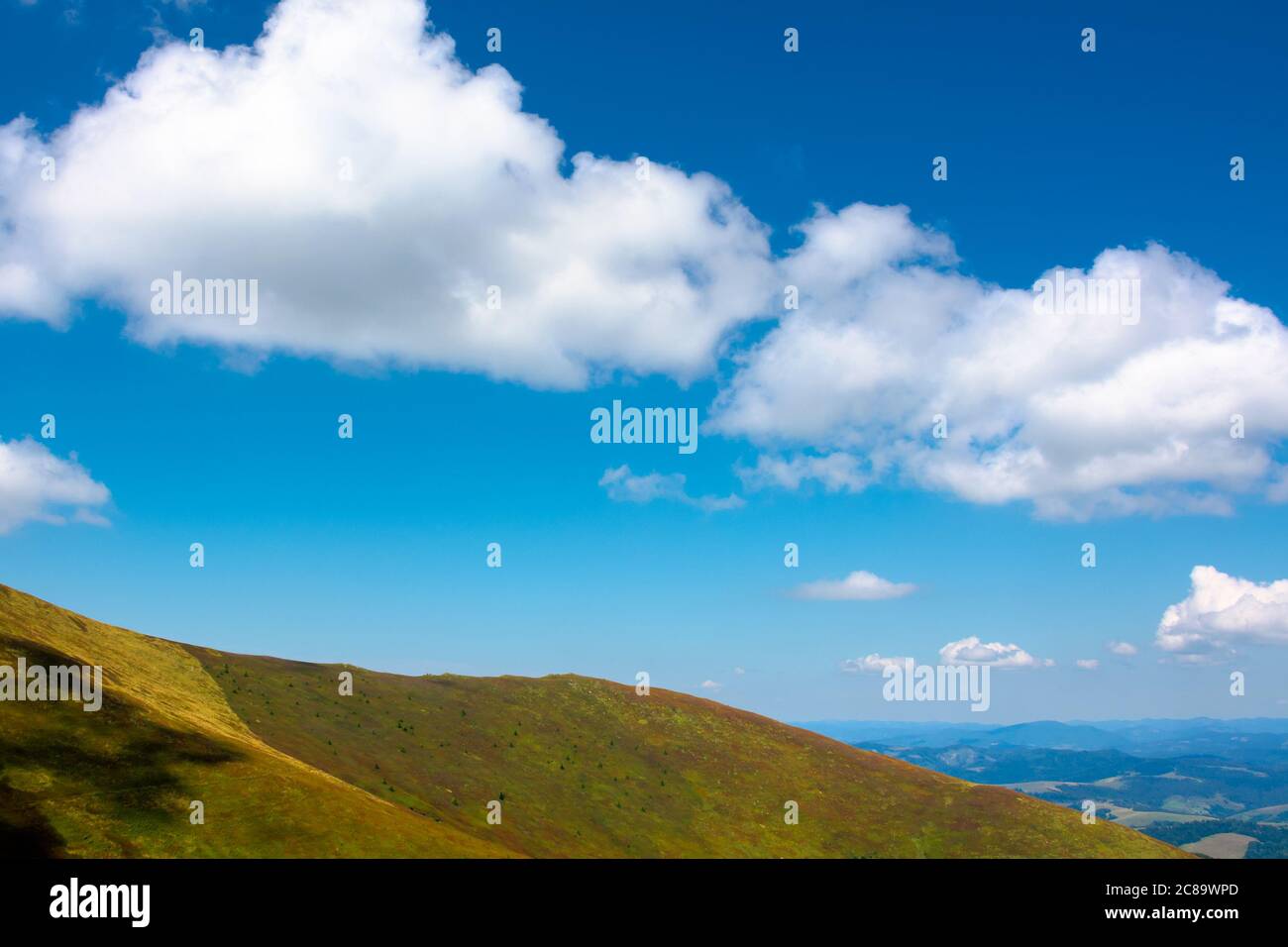 Hügel und Wiesen unter dem blauen Himmel mit Wolken. Hügel und Wiesen unter dem blauen Himmel mit Wolken. Berglandschaft im Spätsommer an einem sonnigen Tag. Stockfoto