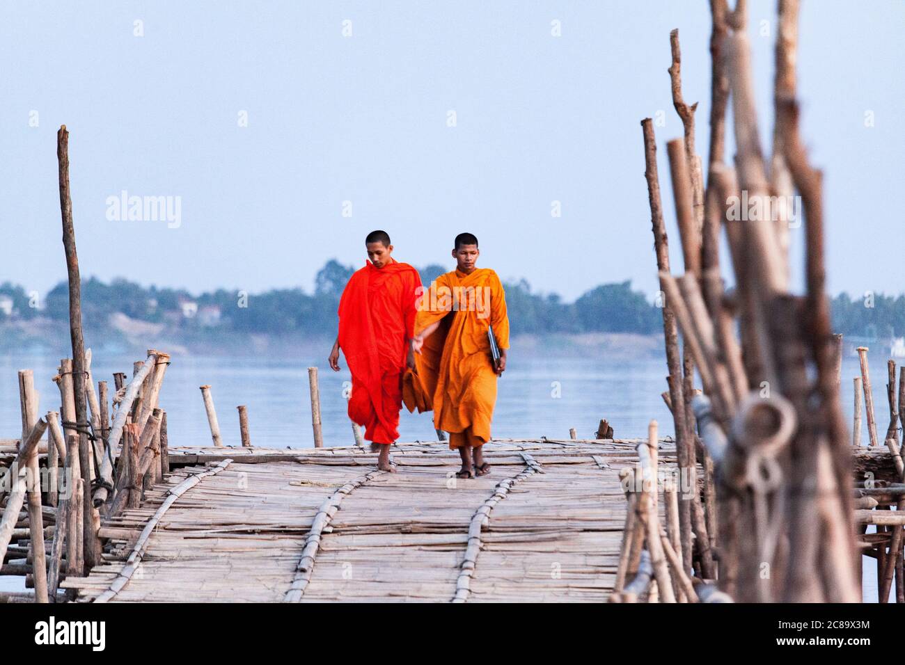 Siem Reap Kambodscha 8/12/2013 Mönche in Orange Überquerung Brücke in der Dämmerung Stockfoto