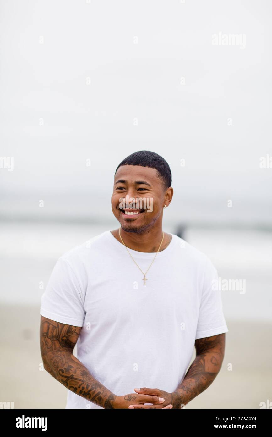 Gemischter Rennmensch lächelt am Strand Stockfoto