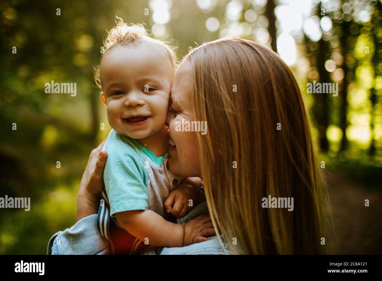 Glücklich Mutter kuscheln Baby junge draußen im Wald Stockfoto