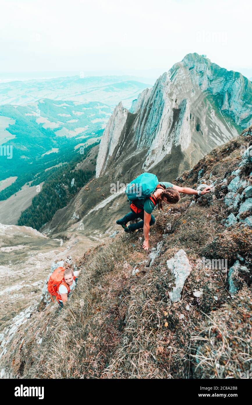 Zwei junge Frauen klettern steiles Gelände vor steilen Berge Stockfoto