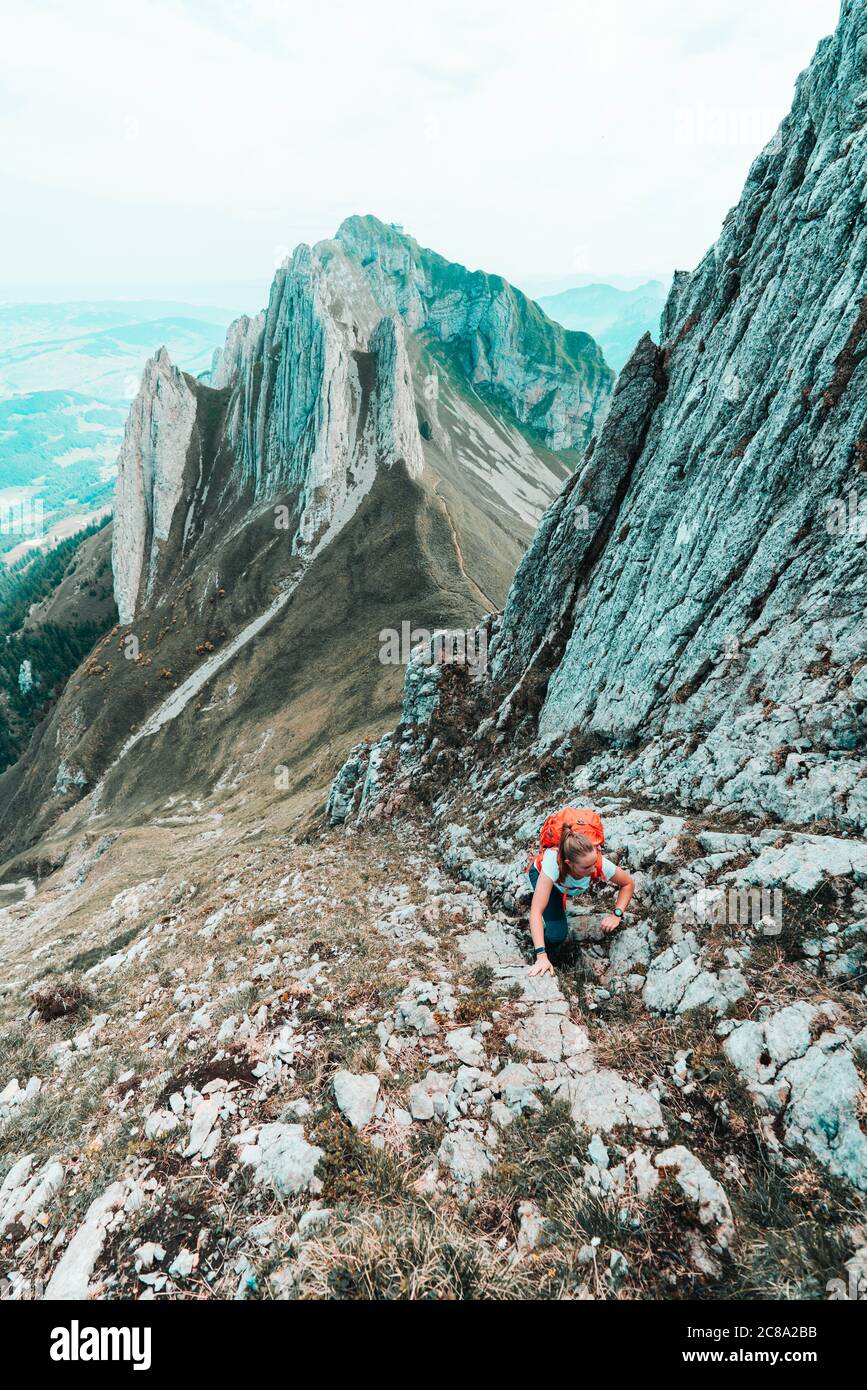 Erhöhte Aufnahme einer jungen Frau, die eine steile Bergwand hinaufklettert Stockfoto