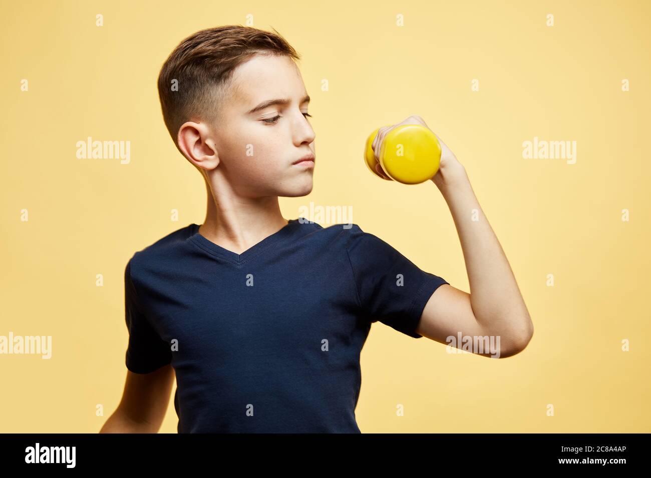 Serious boy mit Hanteln zeigt Bizeps auf Studio Hintergrund Stockfoto