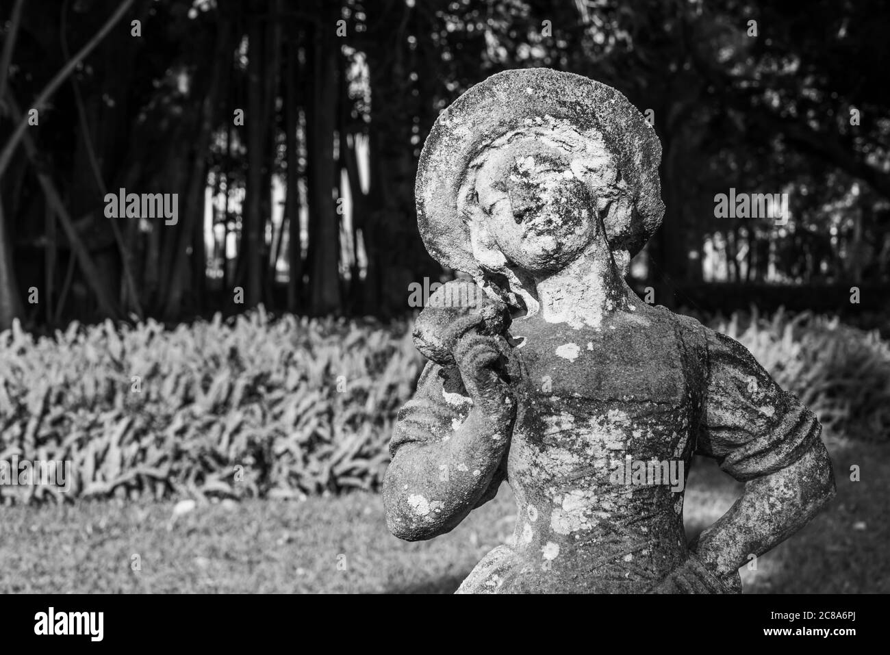 Schwarzweiß-Foto in Nahaufnahme von alt und schmutzig Gartenskulptur eines jungen Mädchens, das eine Pose aufwirft Stockfoto
