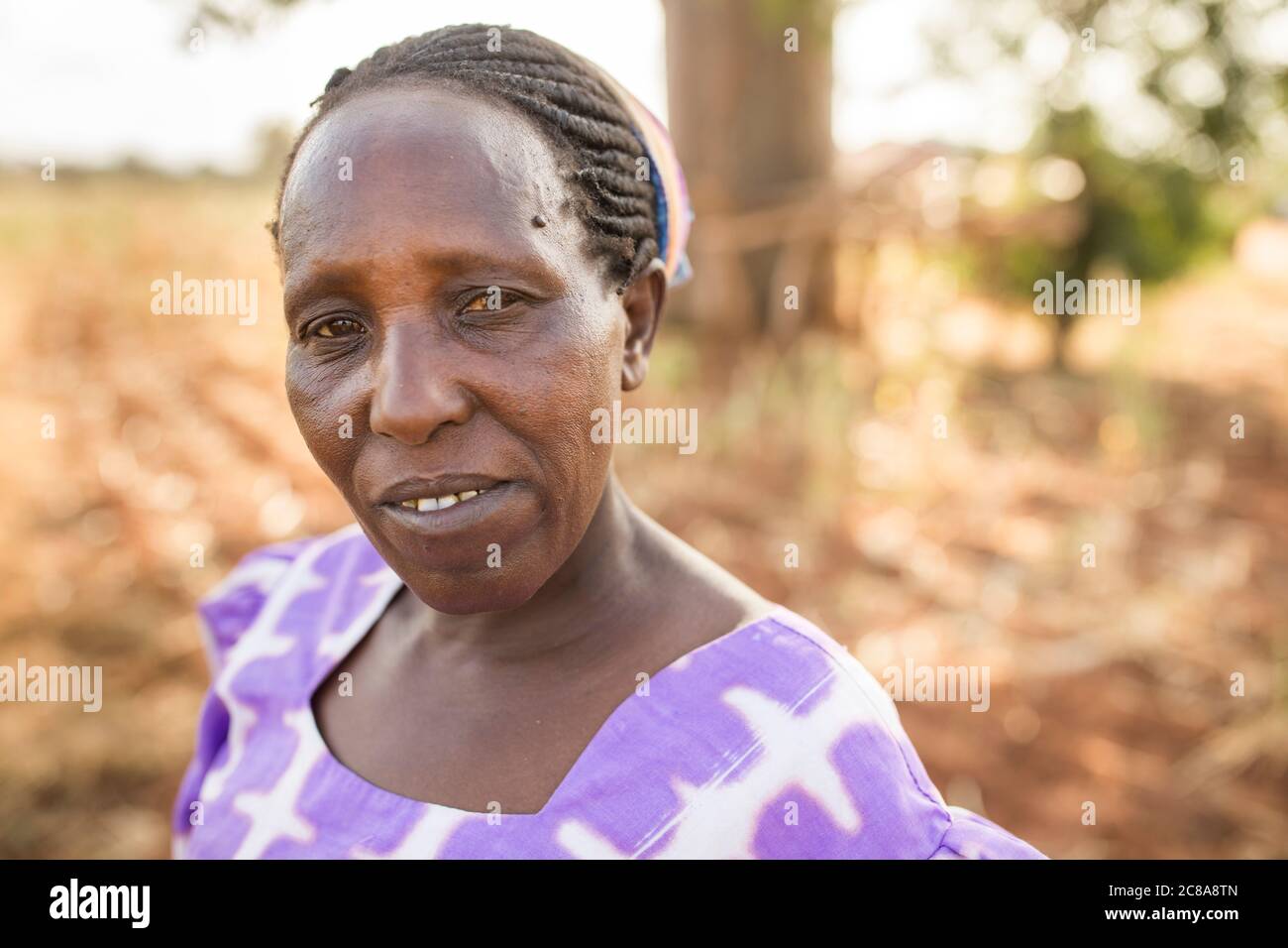 Porträt einer Frau mit einem düsteren Ausdruck in einer trockenen Landschaft im Makueni County, Kenia, Ostafrika. Stockfoto
