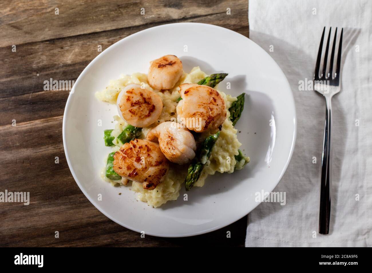 Gebratene Jakobsmuscheln über einem Bett Spargelrisotto Stockfoto