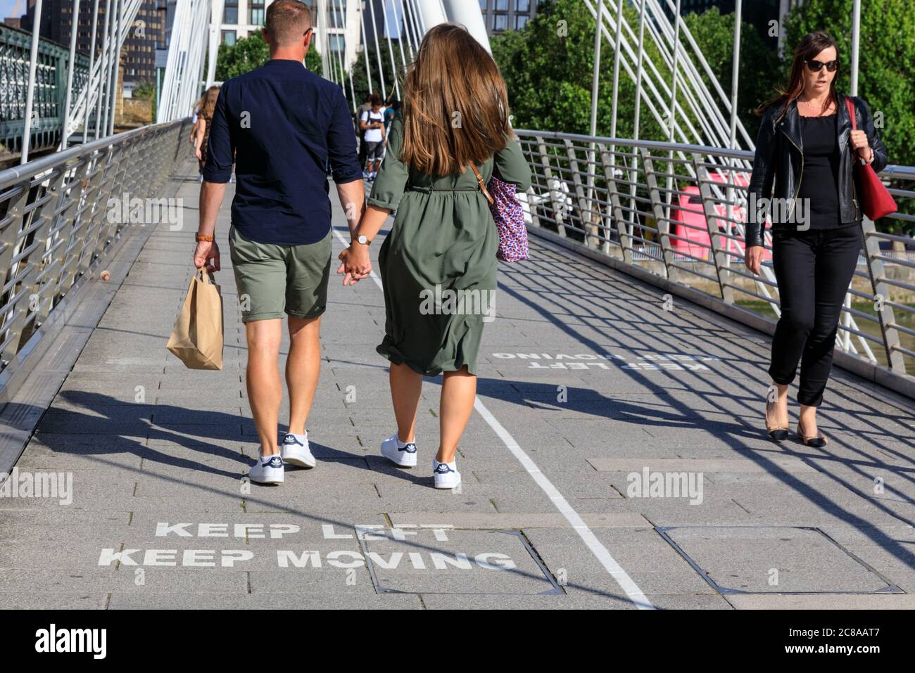 London, Großbritannien. Juli 2020. Die Meldungen „Keep Left, Keep Moving“ auf der Golden Jubilee Bridge erinnern die Londoner daran, Abstand zu halten und sich auf einer Seite der Brücke zu halten. Maskentragen und soziale Distanzierung scheinen zur „neuen Normalität“ zu werden, da sich immer mehr Menschen an die neuen Richtlinien und Empfehlungen gewöhnen. Kredit: Imageplotter/Alamy Live Nachrichten Stockfoto