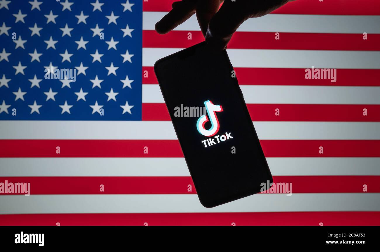 Stone / Großbritannien - Juli 22 2020: TikTok-Logo auf der Silhouette des Smartphones gesehen halten in der Hand mit verschwommener amerikanischer Flagge auf der Rückseite. Neu Stockfoto