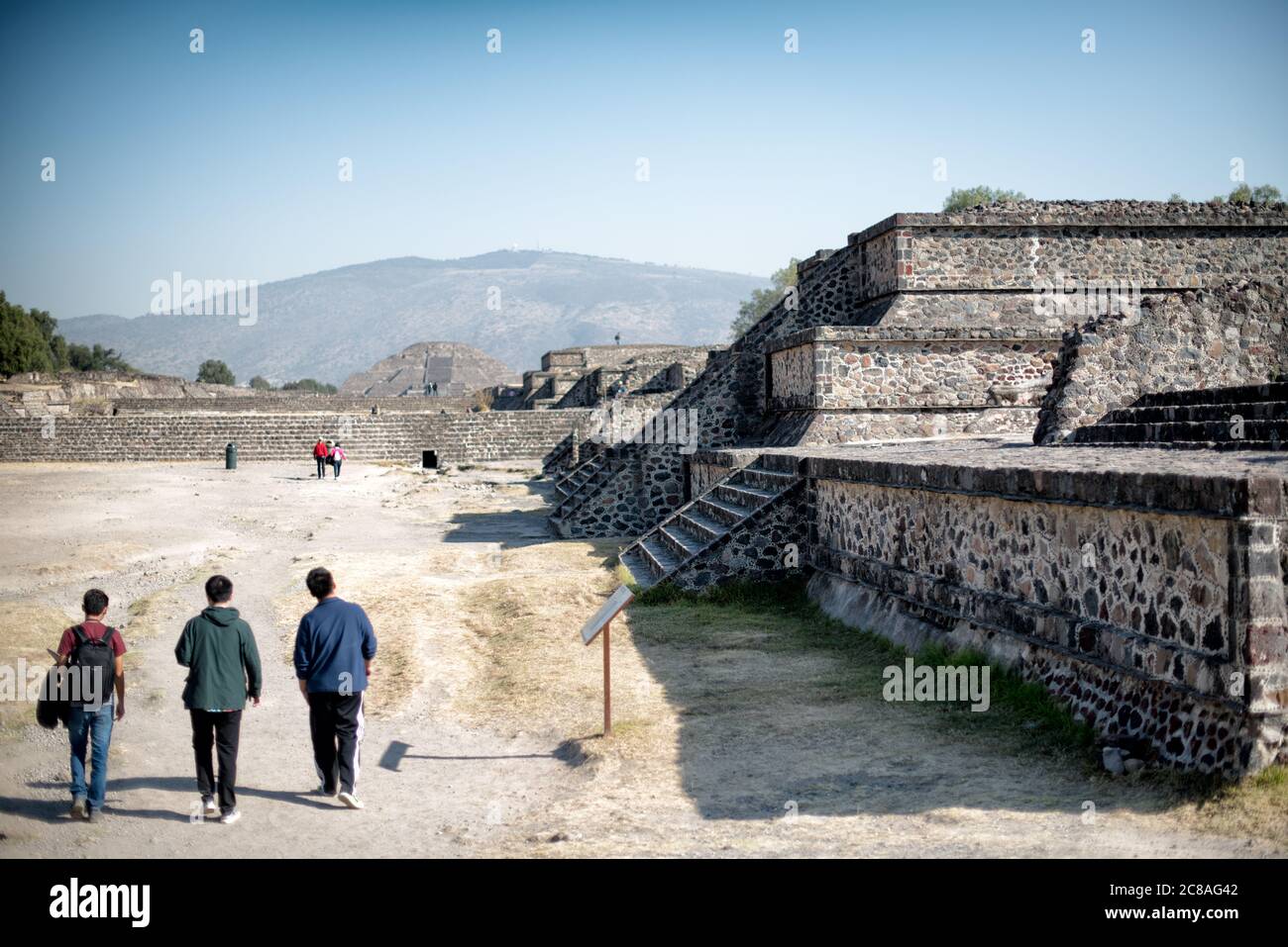 Teotihuacan Avenue Of The Dead Mexiko | TEOTIHUACAN, Mexiko — Besucher gehen die Avenue of the Dead entlang in Richtung der Mondpyramide, der zeremoniellen Achse der antiken mesoamerikanischen Metropole. Die etwa 2,4 Kilometer (1,5 Meilen) lange und etwa 40 Meter (131 Fuß) breite Avenue verbindet die Pyramide mit der Ciudadela und organisierte das strenge Raster der Stadt, das etwa 15,5 Grad östlich des wahren Nordens ausgerichtet ist. Teotihuacan erreichte seinen Höhepunkt zwischen etwa 200 und 550 n. Chr. mit einer gemessenen Bevölkerung von fast 100.000. Stockfoto