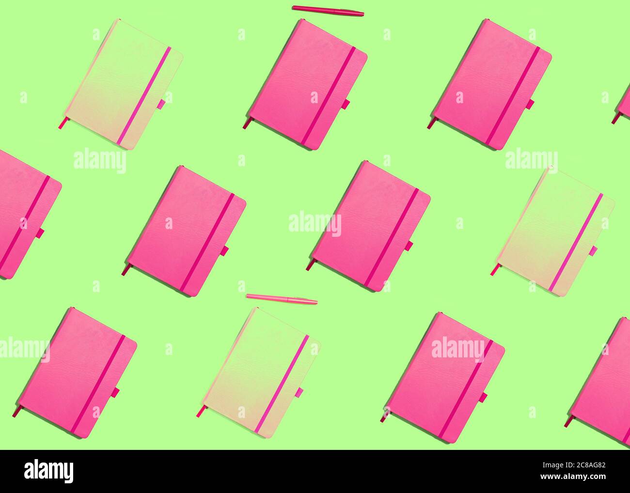 Muster mit rosa Notizbüchern auf grünem Hintergrund, Pop-Stil, lebendige Farben, Konzept der Schule, Kreativität, stationär Stockfoto
