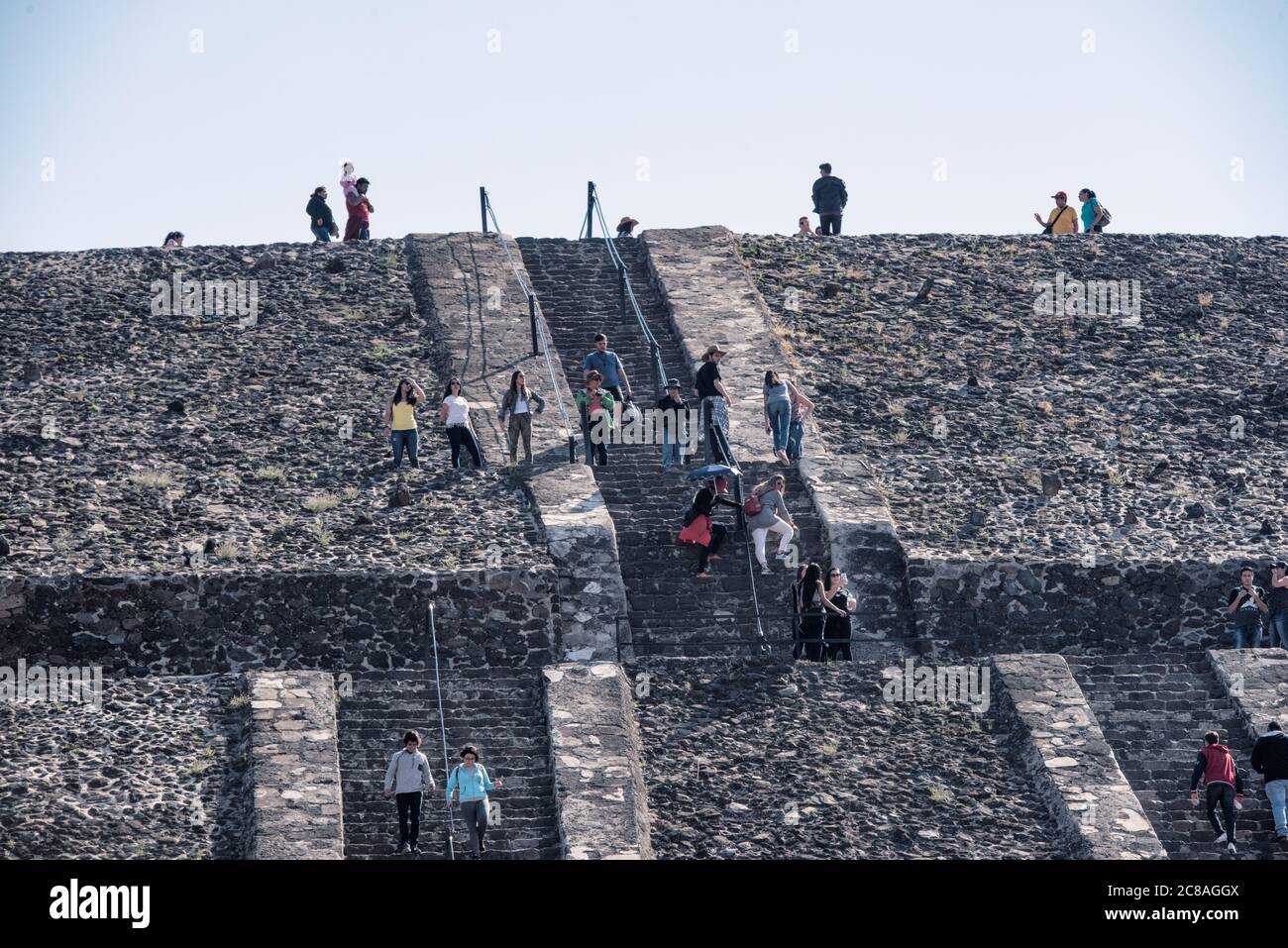 Pyramide der Sonne Besucher Teotihuacan Mexiko // TEOTIHUACAN, Mexiko — Besucher klettern die steilen Stufen der Pyramide der Sonne an der archäologischen Stätte Teotihuacan. Dieses monumentale Gebäude, eine der größten antiken Pyramiden Amerikas, erhebt sich etwa 216 Fuß (66 Meter) hoch und misst etwa 720 Fuß (220 Meter) an seiner Basis. Die Pyramide wurde um 100-450 n. Chr. von der antiken Teotihuacan-Zivilisation errichtet, deren Identität den Archäologen weitgehend unbekannt ist. Teotihuacan war eine der größten Städte in der Antike, mit einer Bevölkerung von bis zu zehn Stockfoto