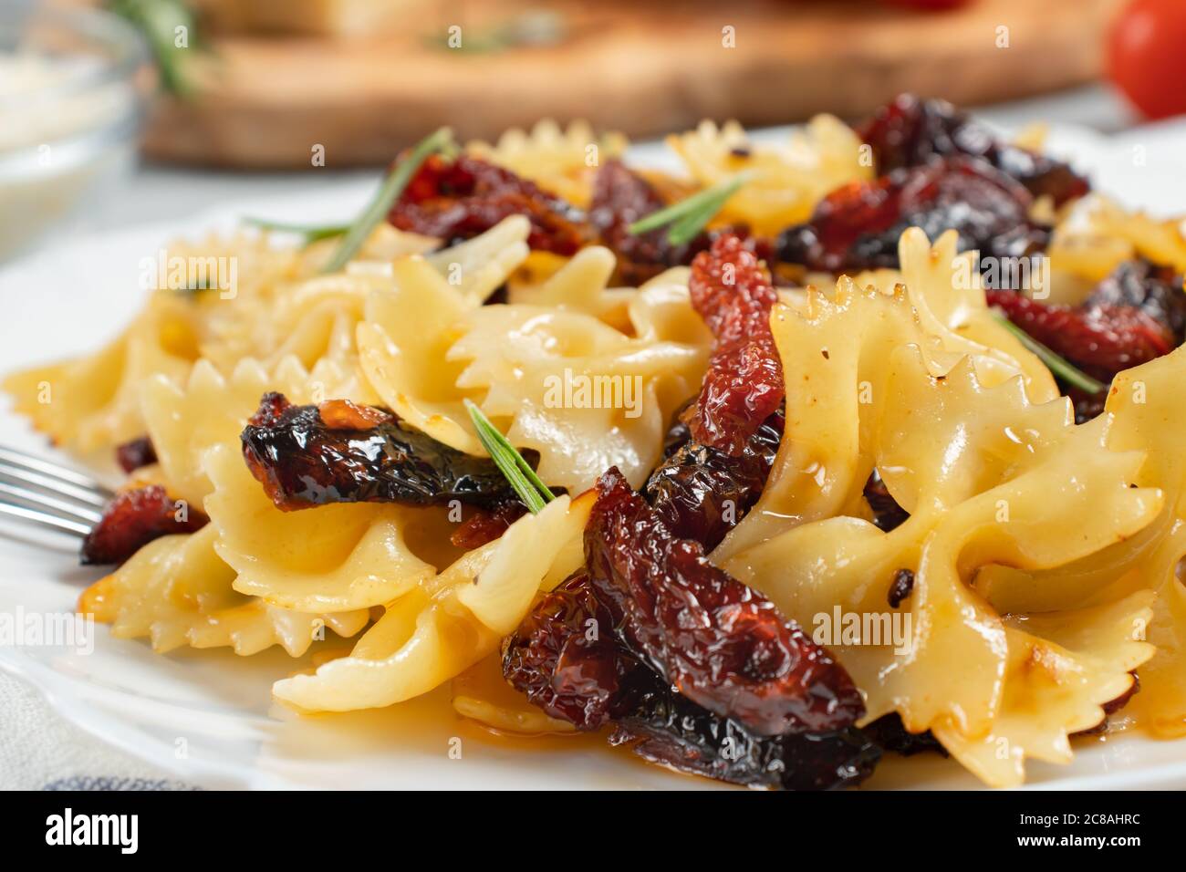 Pasta mit sonnengetrockneten Tomaten auf einem weißen Teller auf dem Tisch. Italienisches Gericht, Nahaufnahme Stockfoto