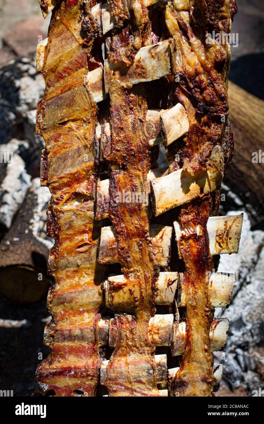 Asado, traditionelles Grillgericht in Argentinien, gebratenes Fleisch auf einem gekreuzten vertikalen Grills gekocht Stockfoto