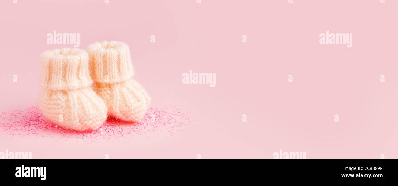 Weiße Schuhe für neu geborene Baby Mädchen oder Jungen auf rosa Hintergrund, Konzept der Erwartung des Babys, Schwangerschaft, Baby-Dusche-Party, niedlich monochrome Karte für Stockfoto