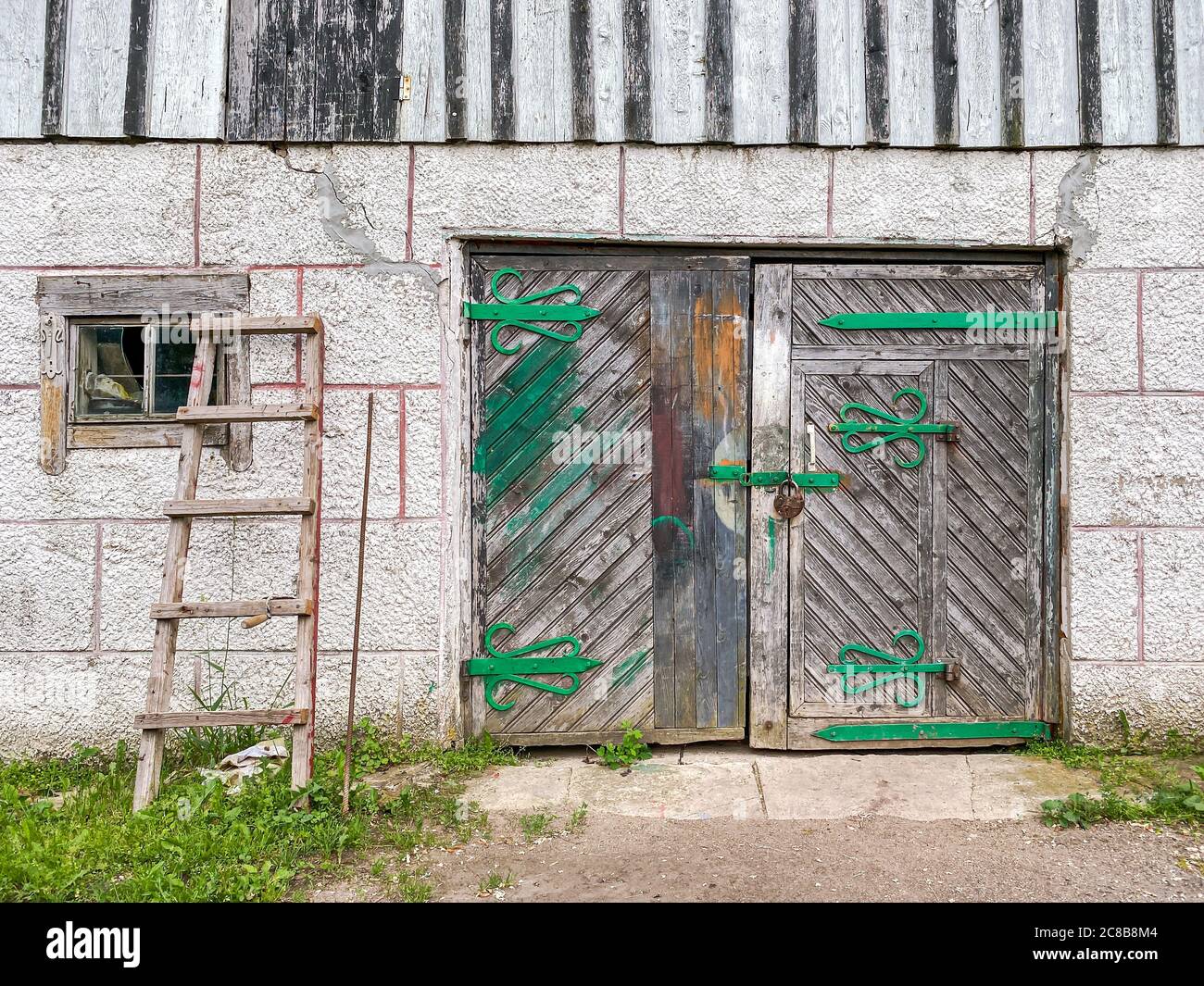 Wand der ländlichen Scheune mit geschlossenen Holztor. Alte rustikale Scheune Tür mit rostigen Metallscharnieren Stockfoto