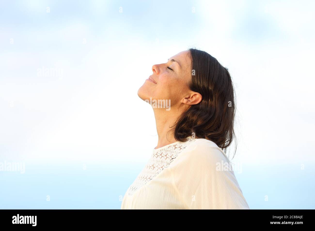 Seitenansicht Porträt einer zufriedenen erwachsenen Frau, die im Sommer frische Luft atmet und am Strand steht Stockfoto